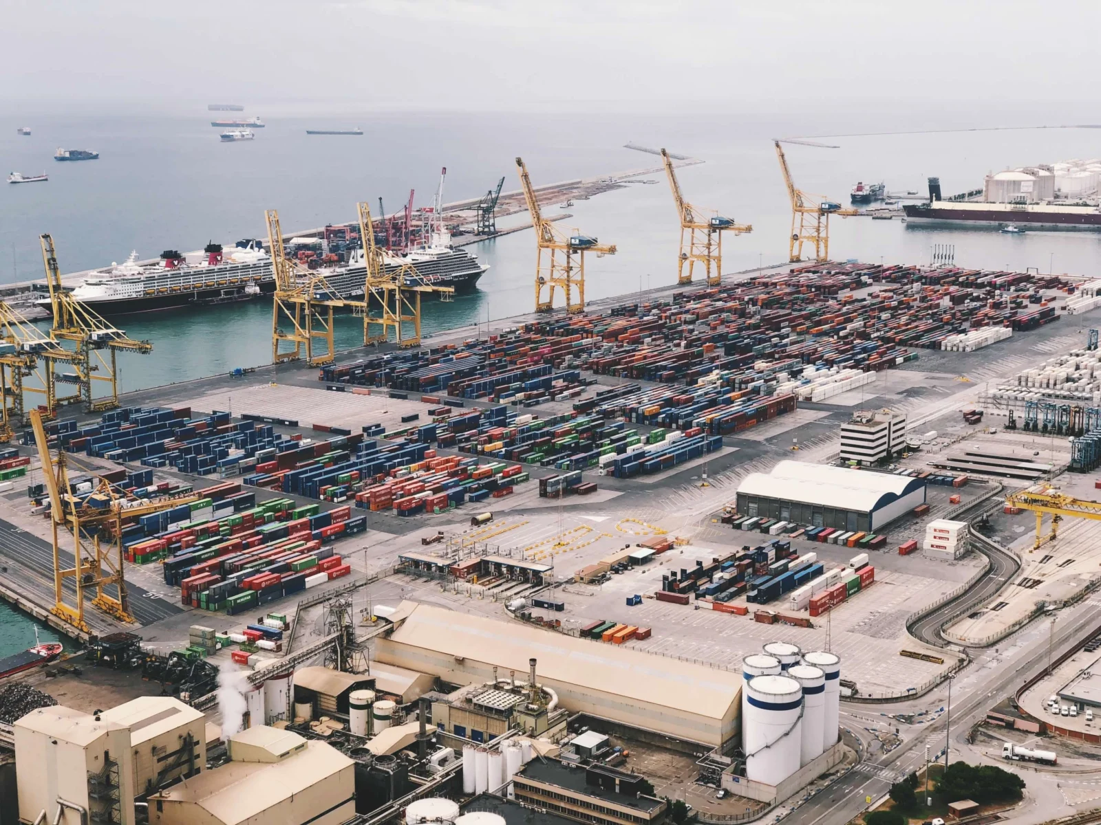 Aerial view of a container port with cranes, stacked containers and ships at sea